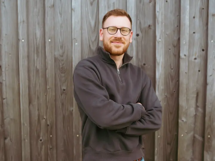 Ferdinand Nefzger von der Webdesign-Agentur FWN Media aus Manching bei Ingolstadt, mit verschränkten Armen vor einer Holzwand im Freien