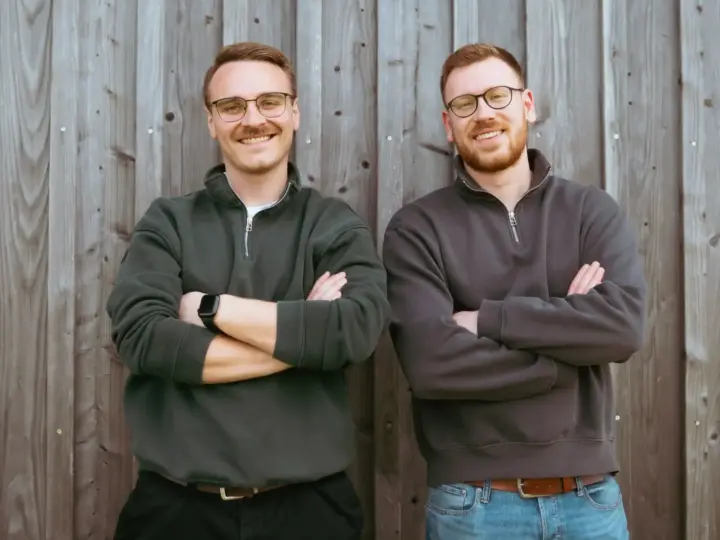 Daniel Weber und Ferdinand Nefzger von der Webdesign-Agentur FWN Media aus Manching bei Ingolstadt, lachend vor einer Holzwand im Freien